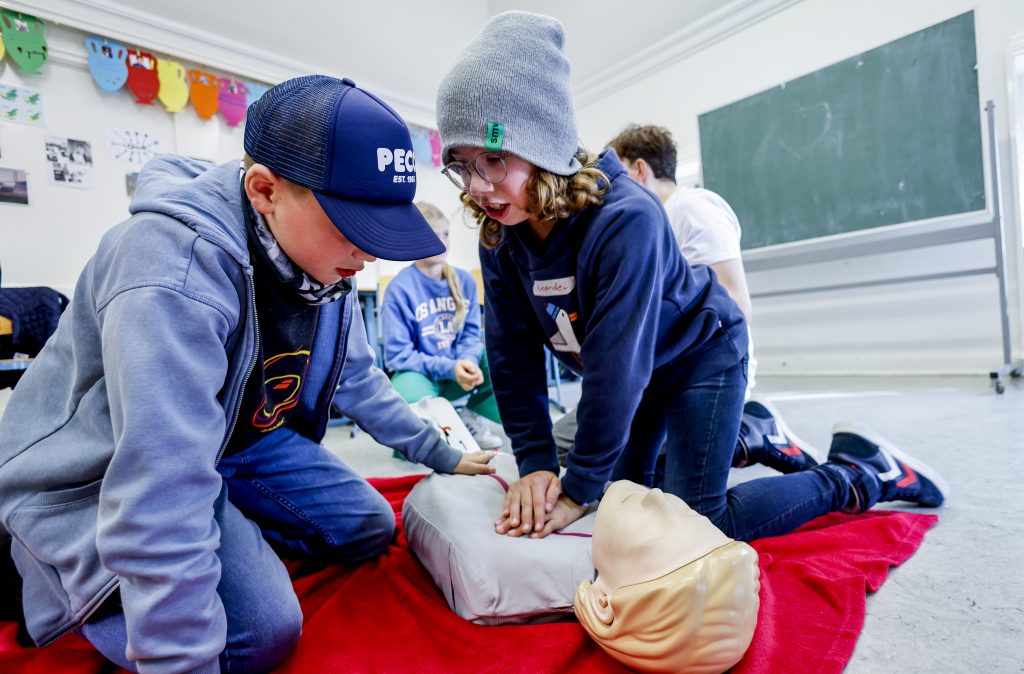 Zwei Kinder üben die Herzdruckmassage an einer Puppe