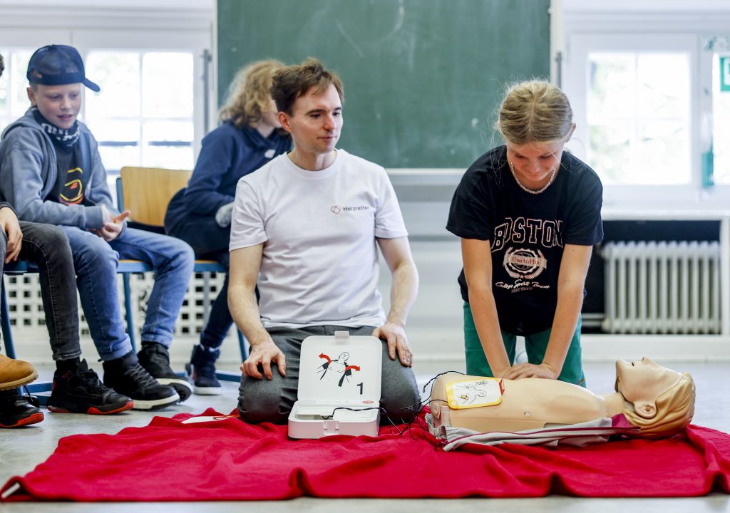 Eine Schülerin übt den Umgang mit dem AED an einer Puppe.