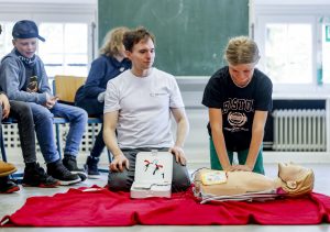 Eine Schülerin übt den Umgang mit dem AED an einer Puppe.