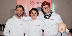 Herzretter Leipzig als Gruppe mit Puppe vor einem Banner der Herzretter